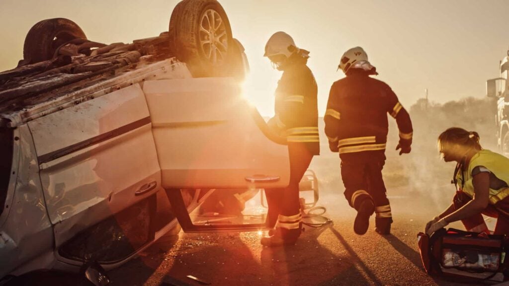 Firefighters and a paramedic at an overturned car after a crash