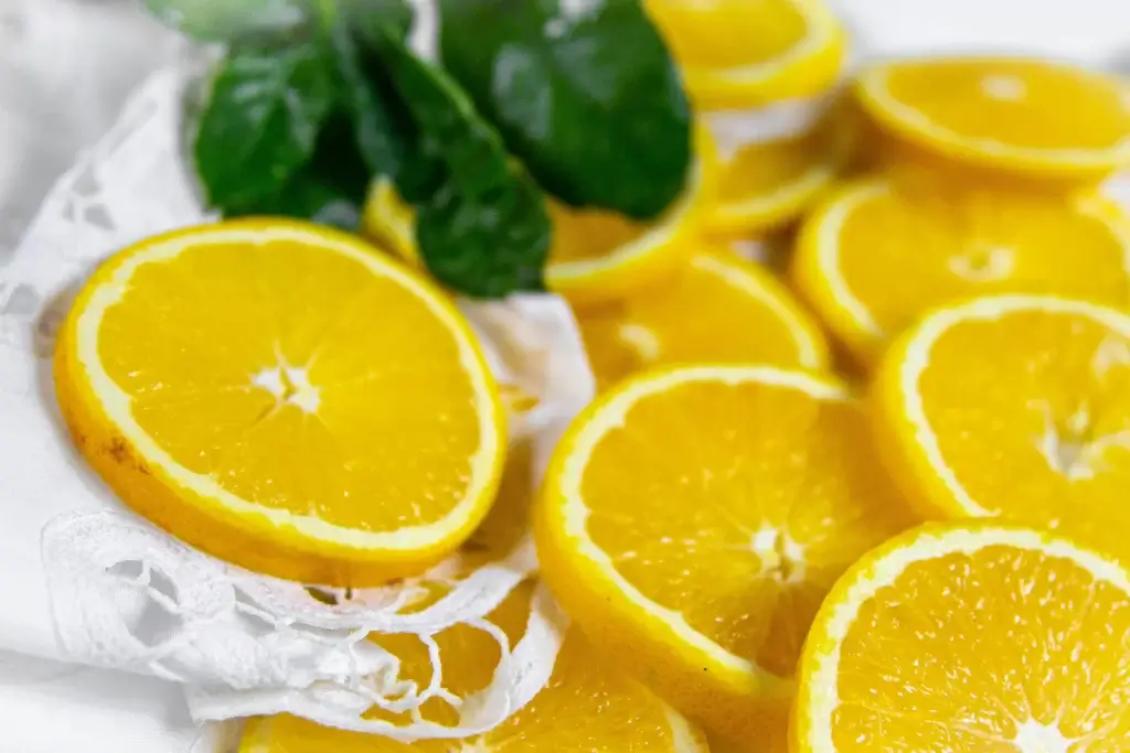 Sliced oranges arranged on a white lace cloth with green leaves in the background, styled with the attention to detail of a Product Liability Lawyer.