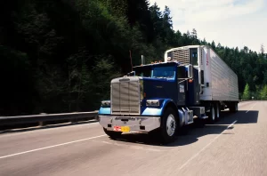 Blue tractor unit hauling a refrigerated trailer along a highway