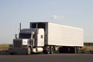 White tractor unit hauling a box trailer on an open road