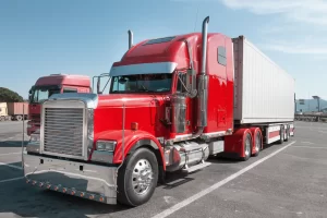 Red tractor unit with a white trailer parked in a lot