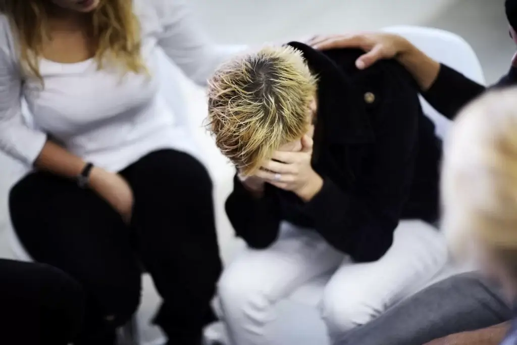 Person sitting alone in a cemetery mourning the loss of a loved one
