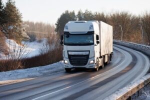 semi-truck navigating winding icy highway through snow-covered winter landscape