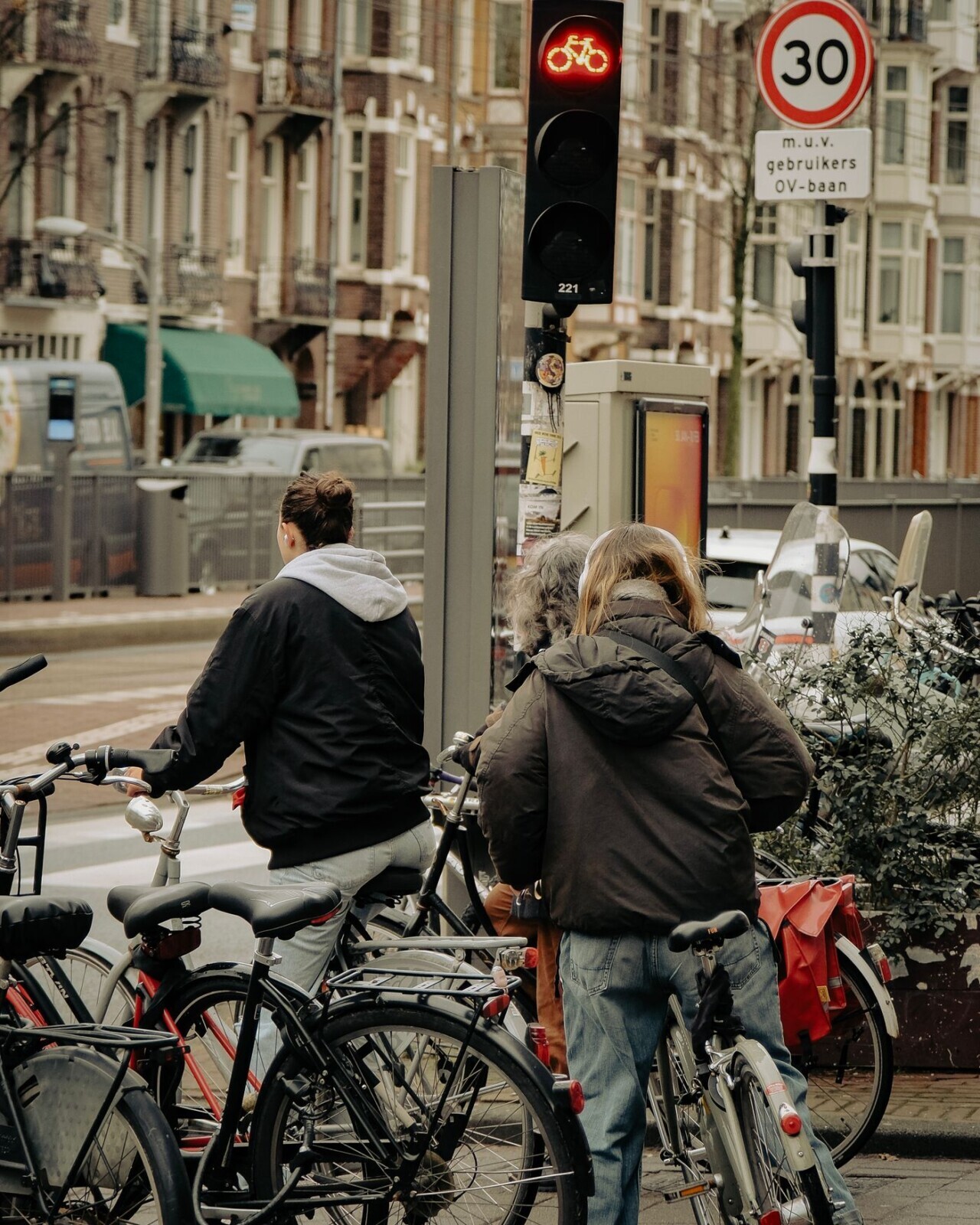 Cyclists waiting at a city intersection in traffic