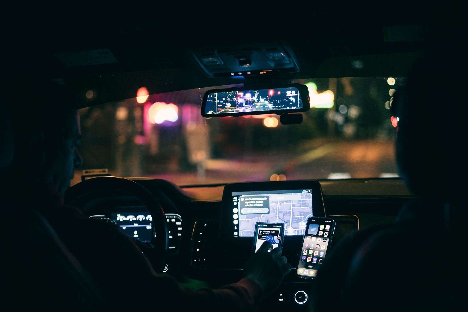 Rideshare driver on a city street at night with the Uber app open on a mounted phone, illustrating an Illinois rideshare accident claim