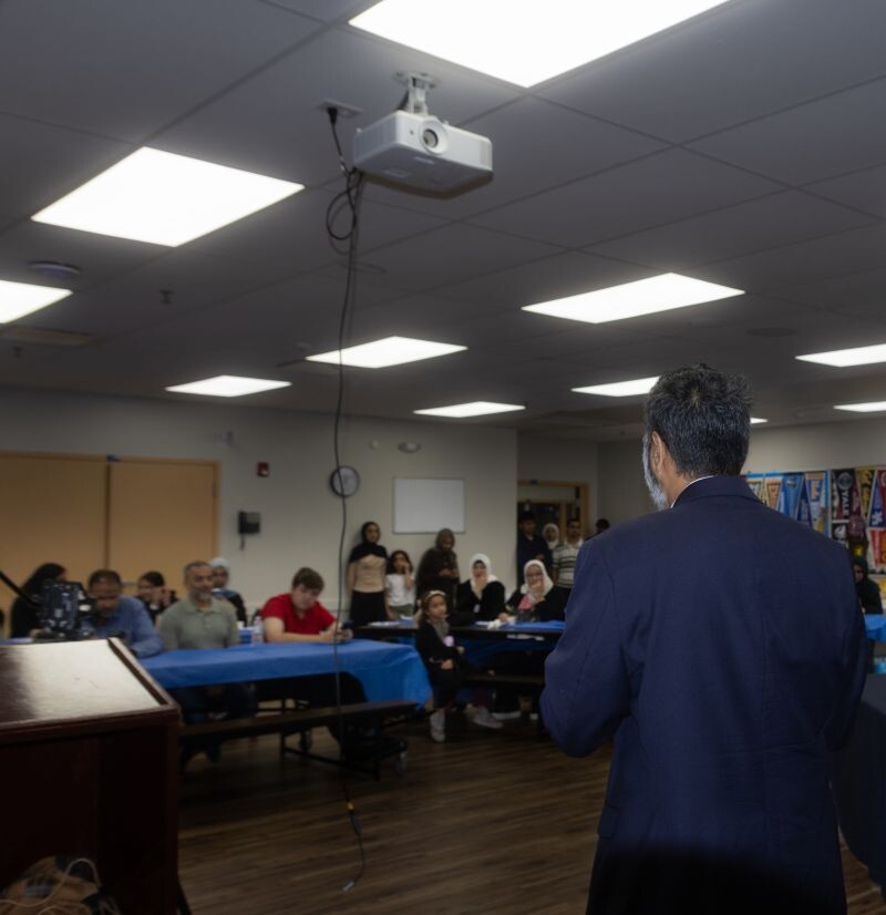 Furqan Mohammed addressing students and families seated at tables during the Muslim Pre-Law Conference in Lombard