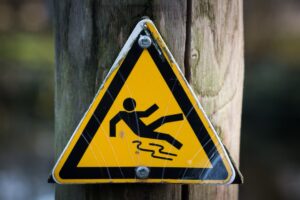 Yellow triangular warning sign showing a person slipping