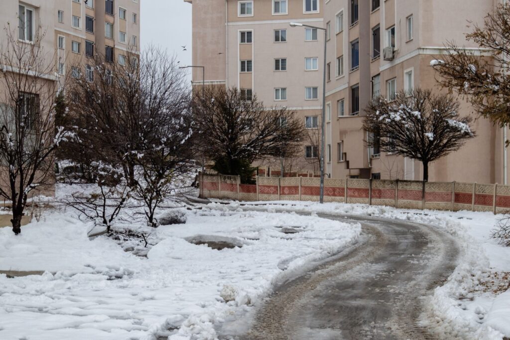 Snow piled beside a plowed residential street with refrozen tire ruts