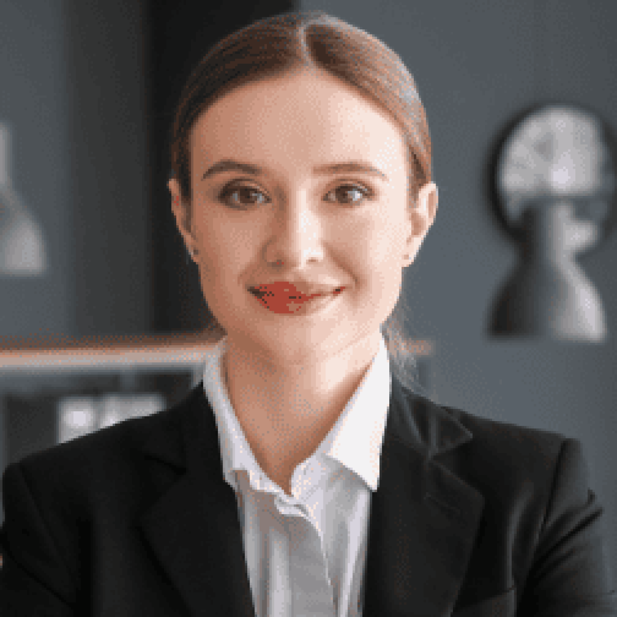A trusted Chicago personal injury lawyer with brown hair tied back, wearing a black blazer and white shirt, stands indoors in an office setting, smiling at the camera.
